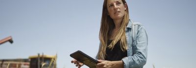 Egy nő áll egy búzamezőn, iPaddel a kezében